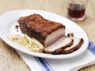 Pancia di maiale con carciofi alla griglia sul piatto — Foto stock
