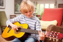 Young boy playing a guitar at home — Stock Photo
