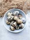 Quail eggs in bowl on blue wooden table — Stock Photo