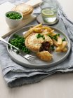 Plate of meat pie with chips and peas — Stock Photo