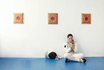 Female fencer sitting on floor using cell phone — Stock Photo