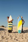 Two young men standing behind surfboards on beach — Stock Photo