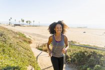 Mid adult woman running along pathway by beach — Stock Photo