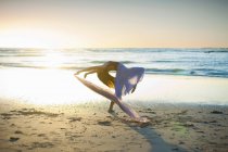 Jovem dançando na praia iluminada pelo sol — Fotografia de Stock
