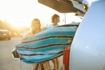 Casal tomando pranchas de surf da bota do carro — Fotografia de Stock