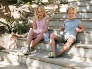 Fratello e sorella seduti su gradini di legno, ritratto — Foto stock