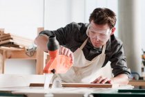 Плотник-мужчина с помощью пилы в мастерской — стоковое фото