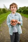 Junge mit einer Handvoll Kartoffeln — Stockfoto