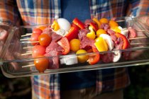 Man holding Tray of raw kebabs for grill — Stock Photo