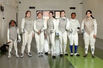 Retrato de esgrimistas femeninas de pie juntas en fila - foto de stock