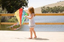 Girl on jetty with kite outdoors — Stock Photo