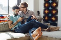Male couple relaxing on sofa together — Stock Photo