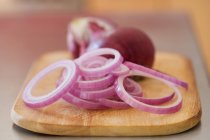 Slices of red onion on wooden board — Stock Photo