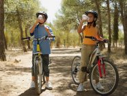 Crianças em bicicletas água potável — Fotografia de Stock