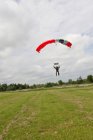 Skydiver landing with parachute in the meadow — Stock Photo