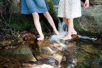 Las piernas de las niñas en el río - foto de stock