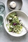 Вид сверху на листья салата и луковицу чеснока в мисках — стоковое фото