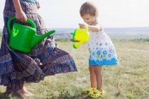 Mother and daughter watering plants — Stock Photo