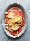 Natureza morta de tomates cortados vermelhos e amarelos em prato — Fotografia de Stock