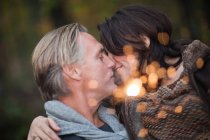 Affectionate mature couple with light from sparkler — Stock Photo