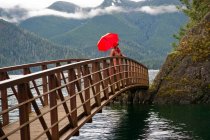 Donna con ombrello su ponte di legno — Foto stock