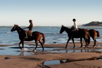Дві жінки катаються на конях на пляжі — стокове фото