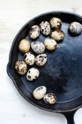 Quail eggs in frying pan on wooden table — Stock Photo