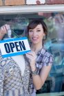Woman hanging open sign on mannequin — Stock Photo