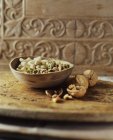 Bol de noix de cajou, pistaches et noix sur planche de bois — Photo de stock