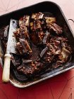 Roasting tin of short ribs braised in black sauce with butchers knife — Stock Photo
