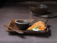 Пумперникель со сливочным сыром, копченый лосось с треснувшим черным перцем на деревянной тарелке — стоковое фото