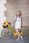 Молода жінка з квітами в кошику велосипеда — стокове фото