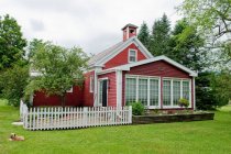 Esterno di bel edificio rosso con giardino, cane sdraiato sull'erba — Foto stock