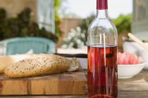Flasche Rosenwein und Brot auf Schneidebrett — Stockfoto