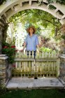 Reife Frau steht unter Gartenbogen — Stockfoto