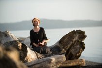 Mujer sentada en madera a la deriva en el mar - foto de stock