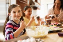 Portrait of girl making cakes with family in kitchen — Stock Photo