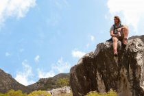 Мужчина-турист сидит на скале с фляжкой — стоковое фото