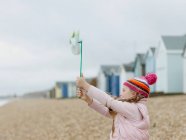 Jeune fille avec moulin à vent sur la plage — Photo de stock