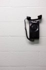 Black vintage telephone hanging on wall — Stock Photo