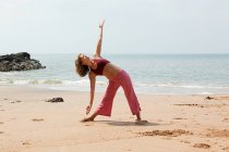 Femme pratiquant le yoga sur une plage — Photo de stock