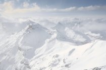Gama de montanhas cobertas de neve com nuvens nebulosas — Fotografia de Stock