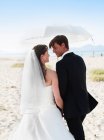 Sposa e sposo che cammina sotto l'ombrellone — Foto stock