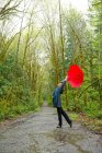 Frau mit rotem Regenschirm auf Waldweg unterwegs — Stockfoto