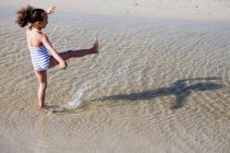 Giovane ragazza che gioca in acqua in spiaggia — Foto stock
