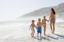 Madre e hijos en una playa - foto de stock