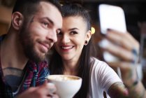 Пара в кафе делает селфи — стоковое фото