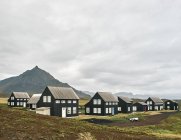 Authentische isländische Häuser mit Berglandschaft und wolkenverhangenem Himmel — Stockfoto