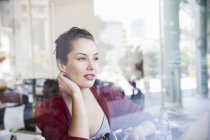 Junge Frau sitzt im Café und schaut aus dem Fenster — Stockfoto