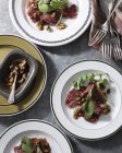 Bistro table with plates of beef carpaccio, rocket and walnuts — Stock Photo